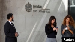 人们站在伦敦证券交易所的入口处玩手机。(2018年8月23日)