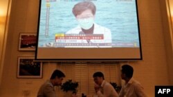 港人聚在餐馆里吃喝,同时餐馆内的电视剧正在爆发香港特首林郑月娥在记者会上发表疫情讲话。(2020年3月23日)