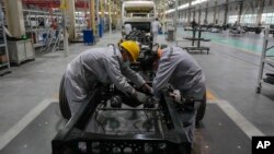 Pekerja merakit kerangka sasis minibus di pabrik manufaktur Tenglong Automobile Co. di Xiangyang, provinsi Hubei, China tengah (foto: dok).