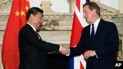 资料照片: 2015年10月21日,英国首相戴维·卡梅伦(右)在伦敦中英商业峰会上与中国国家主席习近平握手