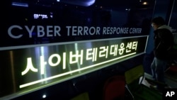 资料照片: 2013年3月21日一行人走过韩国首尔国家警察局网络恐怖应对中心的图标