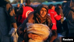 一名从反政府武装控制的阿勒颇东城区转移出来的平民抱着大饼和其他人一道抵达叙利亚反政府武装控制的拉西迪恩镇。(2016年12月15日)
