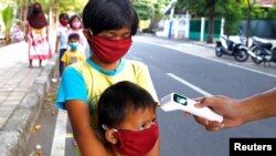 Trẻ em được kiểm tra thân nhiệt trước khi nhận thực phẩm miễn phí tại Jakarta, Indonesia, ngày 14/5/2020.