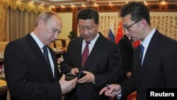 俄罗斯总统普京向中国国家主席习近平赠送手机。(2014年11月9日)