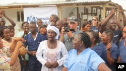 感染了埃博拉病毒的雅丹玛·桑科(中)获得治愈后在离开塞拉利昂一个埃博拉治疗中心时与医疗人员在一起。 (2015年8月24日)