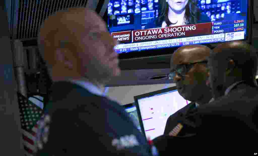 A television on the floor of the New York Stock Exchange features a headline about the shooting in Ottawa. Stocks fell in late afternoon trading on Wednesday, a day after the Standard & Poor's 500 index had its biggest gain of the year, Oct. 22, 2014.