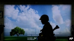 韩国军人在首尔地铁站的反恐演习中走过广告牌(2015年8月19日)