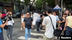 一名中国男子在深圳日本人学校外手捧鲜花致哀悼。(路透社:2024年9月19日)