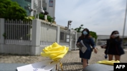 一枚系着“自由花”纸签的黄色玫瑰被摆放在香港苹果日报总部楼外。(2021年6月22日)