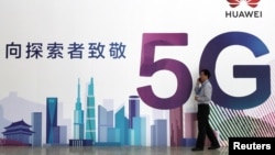 一名男子走过在北京举办的中国国际信息通信展览会的一块华为公司5G技术广告牌。(2018年9月26日)