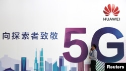 一名男子走过在北京举办的中国国际信息通信展览会的一块华为公司5G技术广告牌。(2018年9月26日)