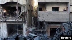 2024年12月13日,巴勒斯坦人在以色列袭击加沙地带中部努塞拉特难民营现场勘察损坏的情况。