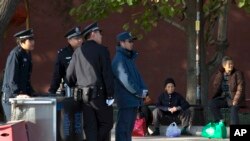 2013年11月12日,老年妇女坐在北京的人行道上,附近是因为中共18届三中全会而增设的保安岗位。