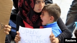 在匈牙利火车站前,一位难民手举标牌(2015年9月4日)。