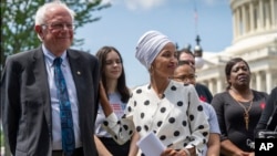 民主党参议员伯尼·桑德斯(左)和众议员伊尔汉·奥马尔(右前一)