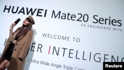 一名模特站在华为在英国伦敦发起的华为Mate20系列的广告牌前。（2018年10月16日）