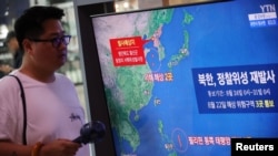 在韩国首尔的一个火车站,一名男子从播放朝鲜发射太空火箭新闻报道的电视屏幕前走过。(2023 年8月24日)