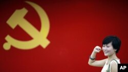 在上海的中共第一次代表大会会址，一名女子在中国共产党党旗下摆出宣誓姿势 （2012年7月1日）
