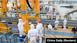 资料照:在中国山东省青岛港,身着防护服的海关出入境人员在检查一艘载有进口原油的油轮。(2022年5月9日)