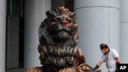 一名工人在香港国际汇丰银行分行前清洁被漆成红色的标志性狮子雕像（2020年1月2日）。