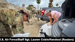 在飓风“弥尔顿”来袭前,一名美国空军士兵与家属一道在佛罗里达州坦帕的麦克迪尔空军基地装填沙袋。(2024年10月7日)