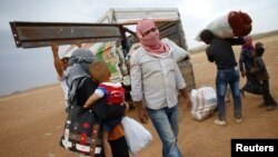 Người Kurd từ thị trấn Kobani ở Syria tải đồ đạc lên xe tải gần biên giới Thổ Nhĩ Kỳ-Syria. Giao tranh tại Kobani đã buộc 200.000 người chạy lánh nạn tới khu vực đông nam của Thổ Nhĩ Kỳ.
