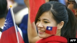 资料照:一名台湾女子脸颊上贴着台湾旗帜并手举台湾旗帜参加集会。