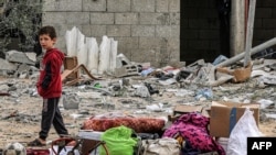 2024 年 3 月 26 日,以色列与激进组织哈马斯在巴勒斯坦领土上持续发生冲突,以色列轰炸加沙地带南部拉法。一名男孩站在从被炸的一栋大楼中搜寻出来的物品旁。