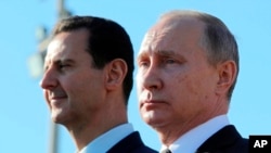 俄罗斯总统普京在叙利亚总统阿萨德陪同下在叙利亚哈迈尼姆航空基地检阅部队。(2017年12月11日)