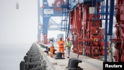 中国中远海运集团在秘鲁钱凯建设的新的大型港口内,工人站在龙门吊旁。(2024年10月24日)