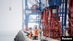 中国中远海运集团在秘鲁钱凯建设的新的大型港口内,工人站在龙门吊旁。(2024年10月24日)
