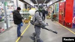 在俄罗斯首都莫斯科,一名身着防护装备的人在喷洒消毒剂。(2020年4月9日)