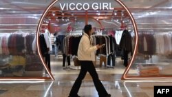 一名女子走过北京一个商场内的一家挂满冬衣的服装店。(2024年12月3日)