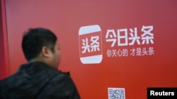 一名男子走过北京街头张贴的新闻类民营企业字节跳动公司(Bytedance}的新闻平台今日头条的广告。 (2017年10月26日)