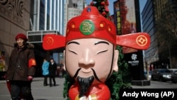 资料照片:一名妇女正路过北京一处购物中心外面的财神爷雕像。(2011年2月28日)