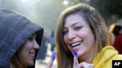 2012年12月5日两位埃及女选民在开罗的投票所投票之后展示她手指上的投票蓝印.