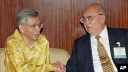 1996年9月,中国人大常委会副委员长王光英(右)和马来西亚政府经济顾问握手。据说,目前在逃的张潲煌的(外)祖父是“光大”公司的创始人王光英