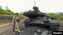 资料照片:在哈尔科夫地区,一名乌克兰军人走过一辆被击毁的俄军T-90M坦克。(2022年5月9日)