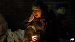 一名悼念者2012年12月16日在康涅狄克州纽敦举行的悼念枪击案死难者的烛光晚会上聆听奥巴马总统通过扩音器讲话的时候留下泪来