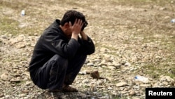 一名伊拉克人蹲在地上掩面痛哭。在伊拉克军队与“伊斯兰国”激进分子在摩苏尔交战期间,他的儿子被空袭炸死。(2017年3月17日)