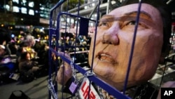 资料照:在韩国首尔国会外举行的要求弹劾总统尹锡悦的集会上,示威人群制作了一座显示尹锡悦锒铛入狱的讽刺雕像。(2024年12月13日)