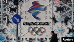 北京街头一名男子走过一幅北京冬奥会的宣传画前。(2022年1月25日)