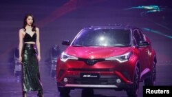 2018年4月24日,在北京车展举行之前的启动仪式上,车模站在丰田 IZOA 汽车旁边。美国汽车制造商联盟估计,对进口商品征收25%的关税将使每辆新汽车的平均价格上升5800美元。