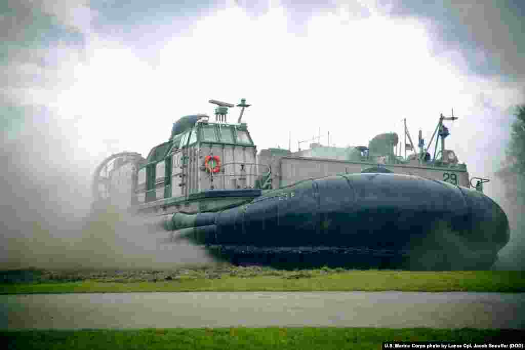 美国海军陆战队员搭载一艘水陆两栖突击车和登陆艇(带有气垫),在关岛海军基地演练抢滩登陆。(2015年9月17日)