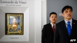 2017年10月13日,被香港媒体认定为前美国中央情报局特工李振成(音译)的男子(打蓝色领带者)站在佳士得香港展厅的保安员前面,身后是达芬奇的画作 。
