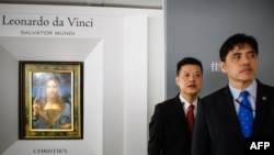 2017年10月13日,被香港媒体认定为前美国中央情报局特工李振成(音译)的男子(打蓝色领带者)站在佳士得香港展厅的保安员前面,身后是达芬奇的画作 。