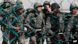 2013年3月21日,韩国士兵在非军事区附近演习时走过一道铁丝网。