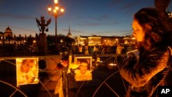 Một người phụ nữ đứng trước các bức ảnh của nạn nhân vụ tai nạn máy bay được đính lên hàng rào tại Quảng trường Cung điện, St.Petersburg, Nga, ngày 3/11/2015.