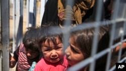 在边境关口等待从土耳其被送回叙利亚的小难民。(2015年6月17日)