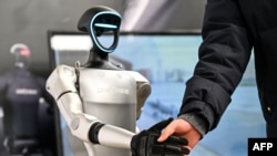 2025年2月21日,在上海人工智能产业协会组织的全球开发者先锋大会上,一名男子与宇树科技的一款人形机器人握手。